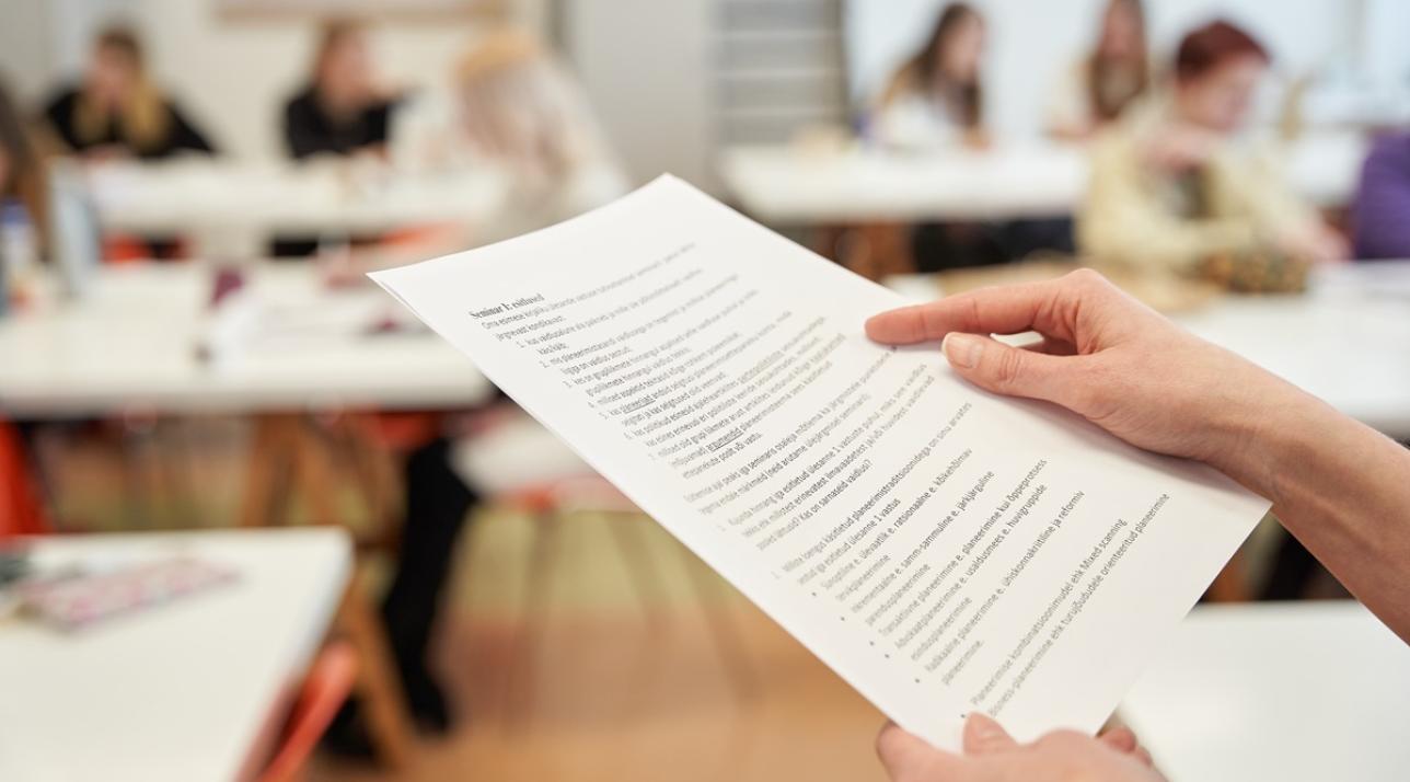 Inimene näitab näpuga paberi peale