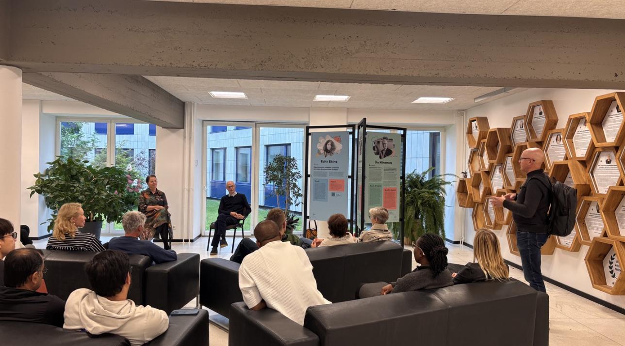 Publik istub diivanitel, nende eest naine ja mees räägivad istudes