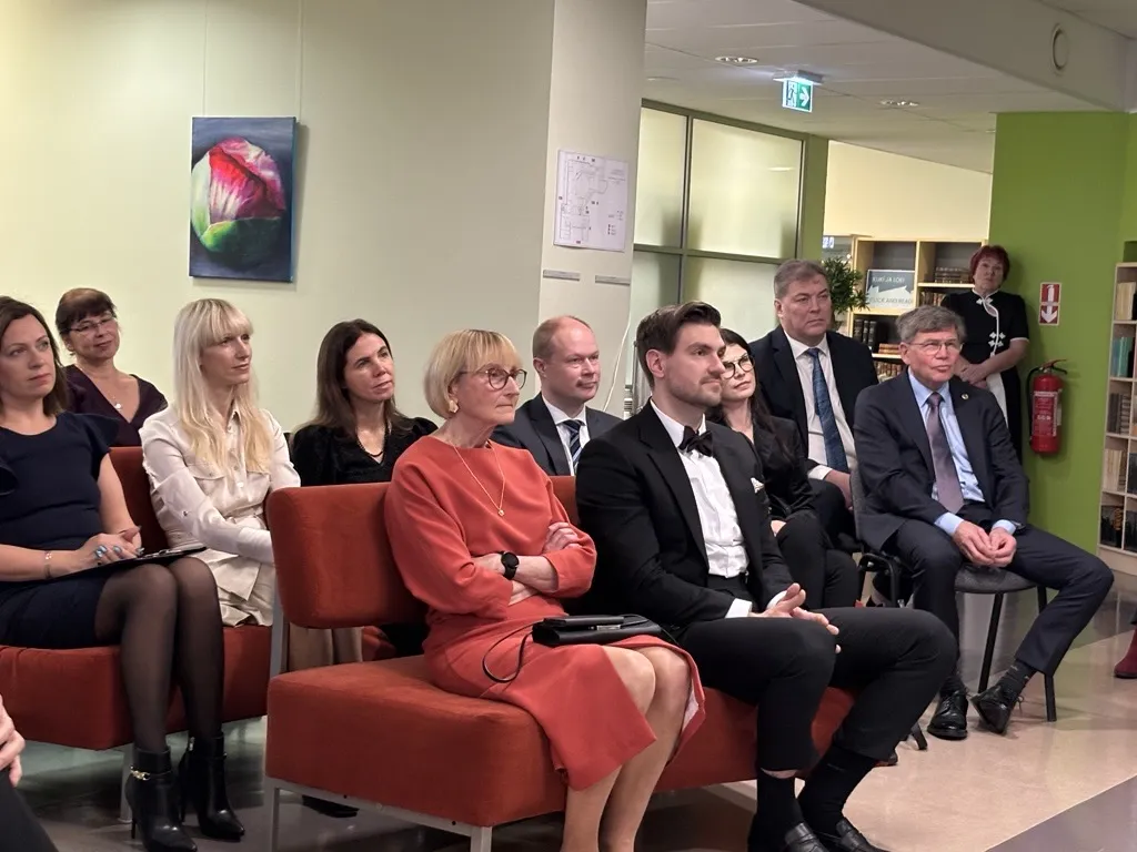 Inimesed istuvad pidulikus raamatukoguruumis ja kuulavad ning vaatavad esinejat