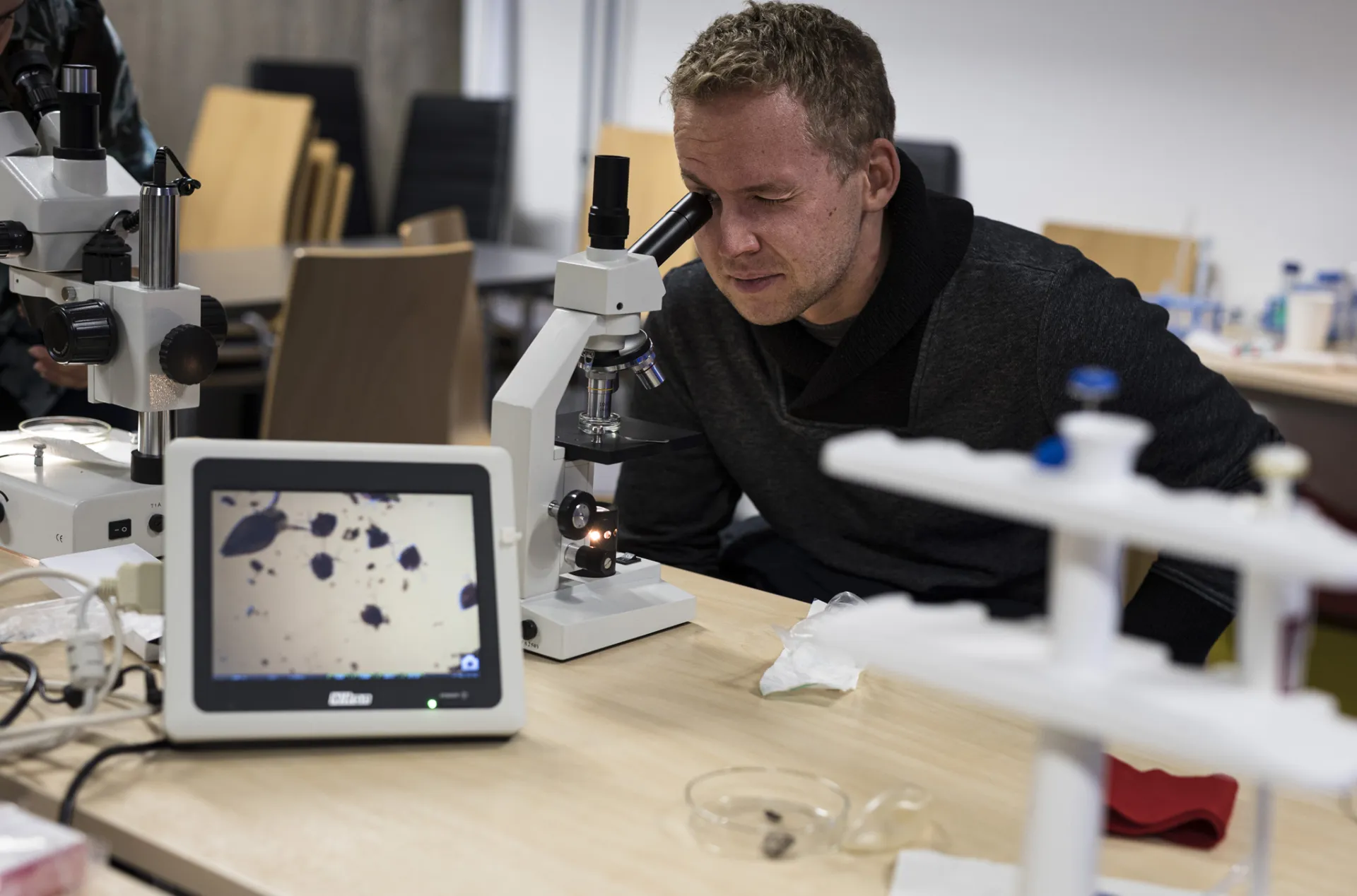 Man is sitting and looking into the microscope