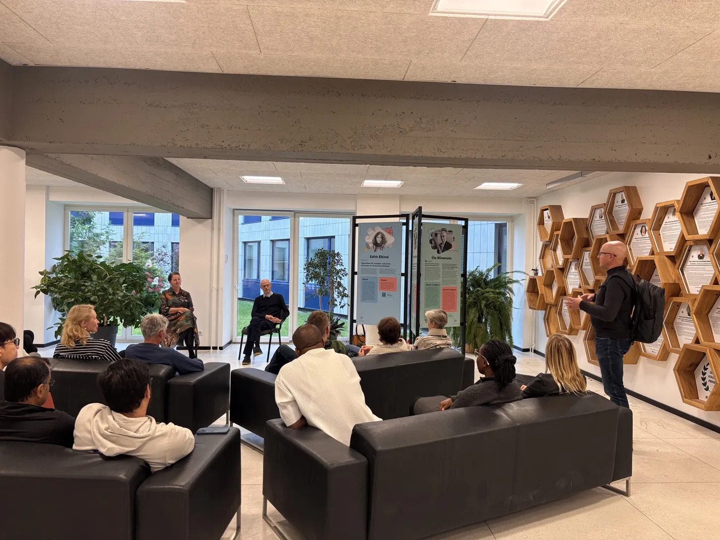 Publik istub diivanitel, nende eest naine ja mees räägivad istudes