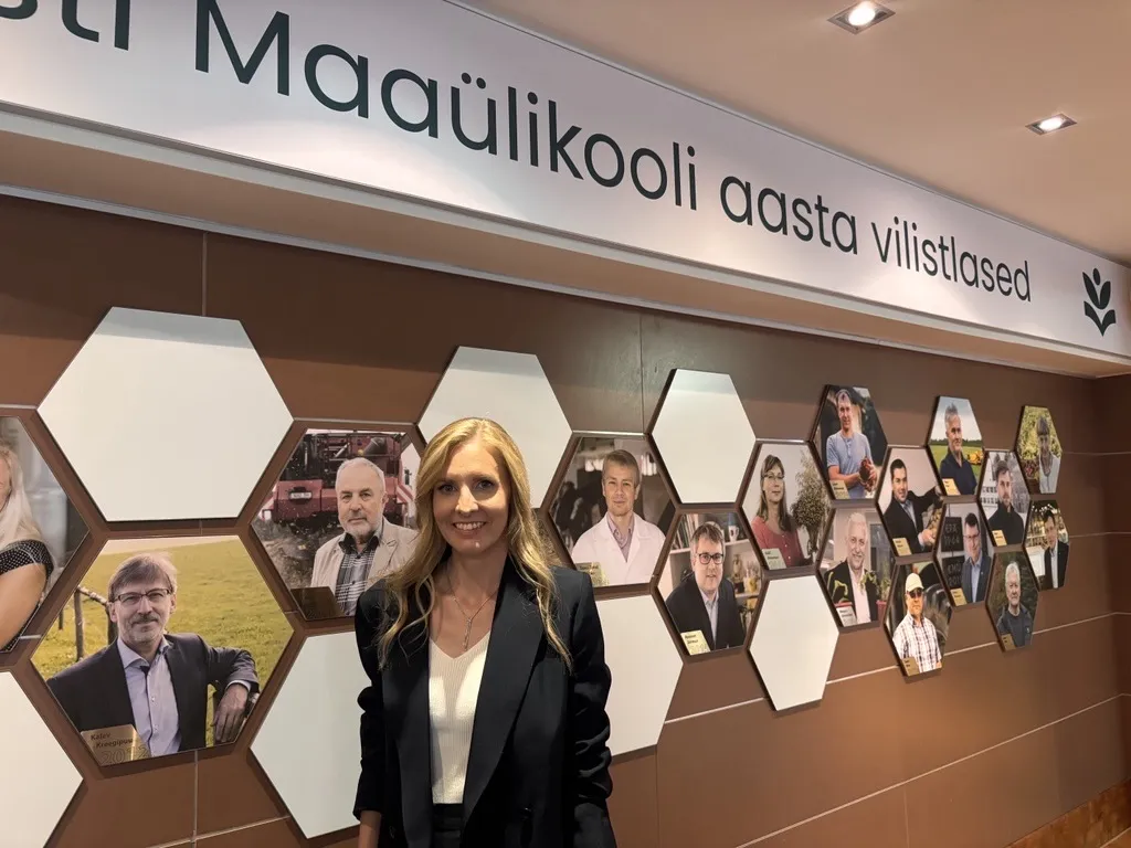 Naine seisab seina ääres, taamal inimeste pildid