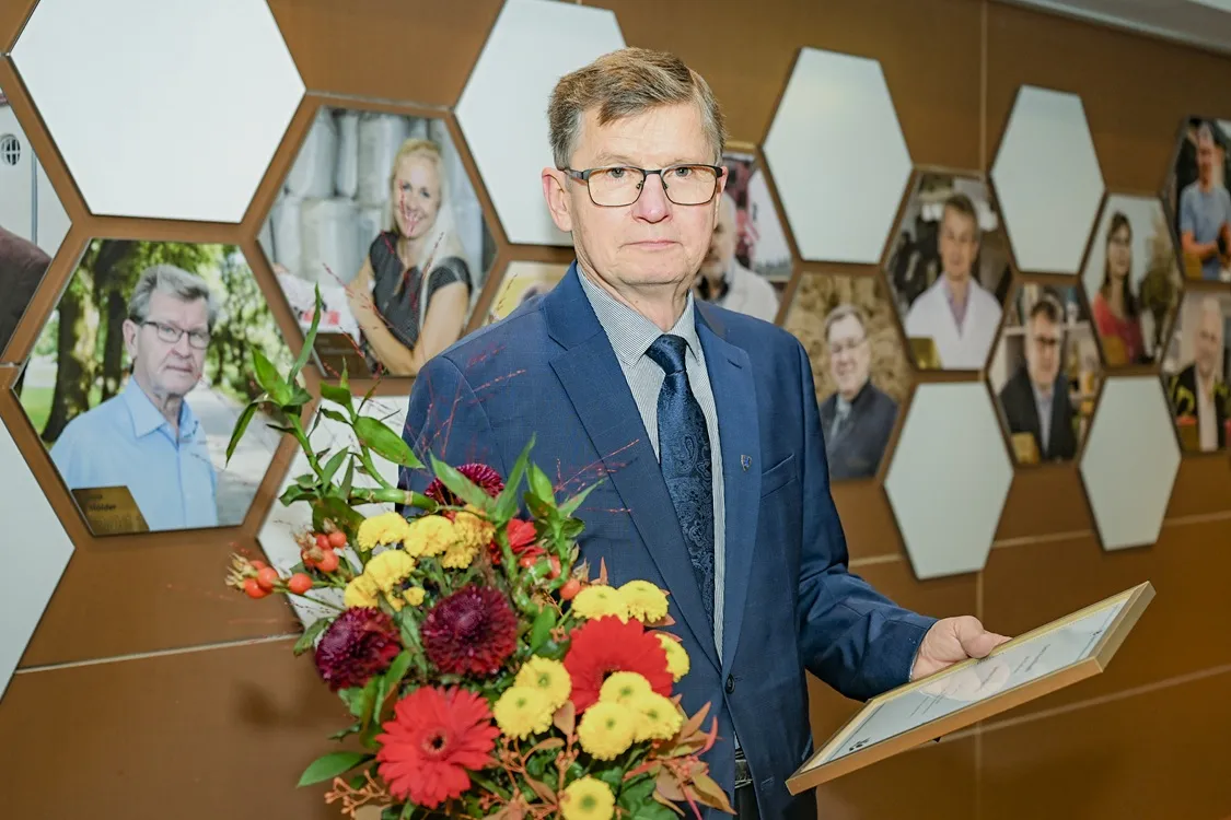 Mees seisab lillede ja diplomiga